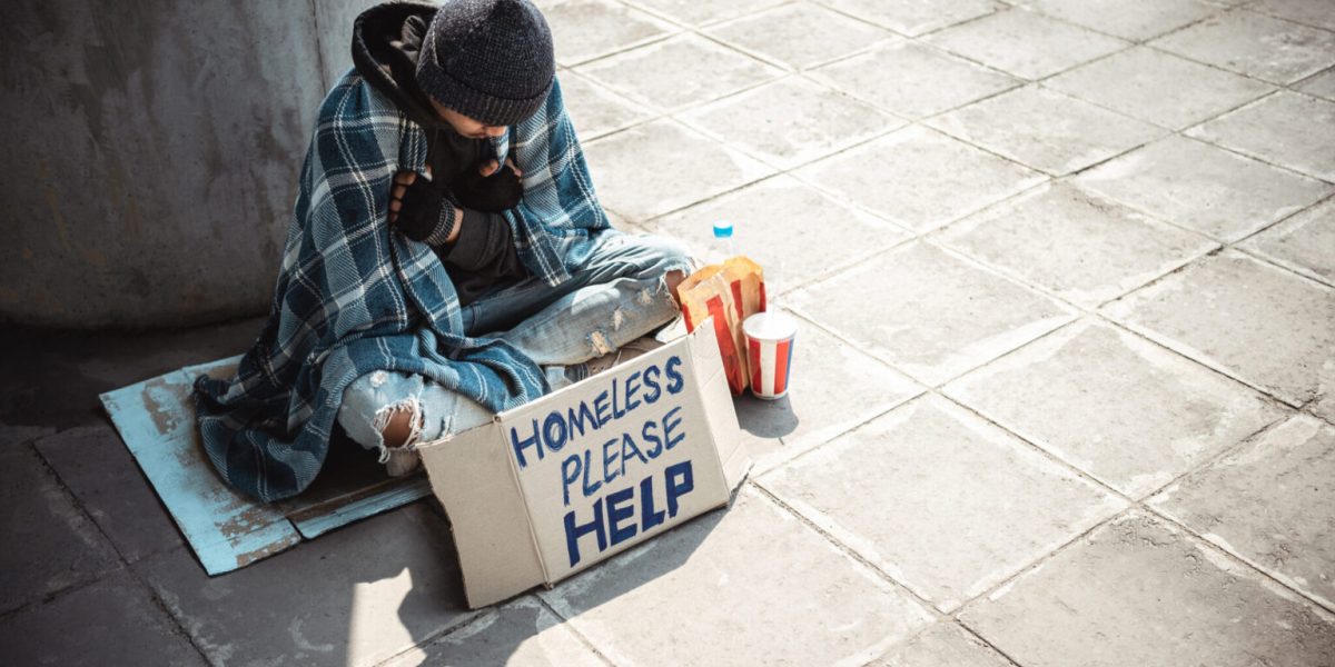 One man, young homeless sitting on the street and begging.
